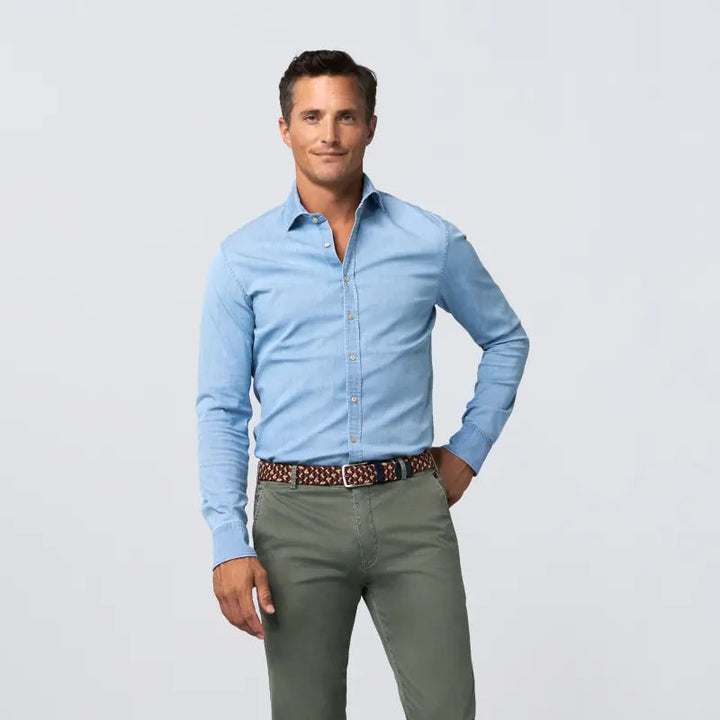 Man wearing a light blue shirt and green pants with a belt on a white background